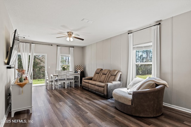 living room with dark wood-type flooring, visible vents, plenty of natural light, and ceiling fan