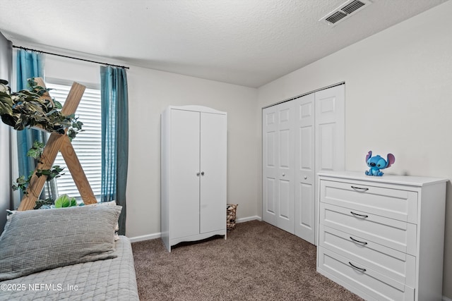 bedroom with baseboards, a textured ceiling, visible vents, and carpet flooring