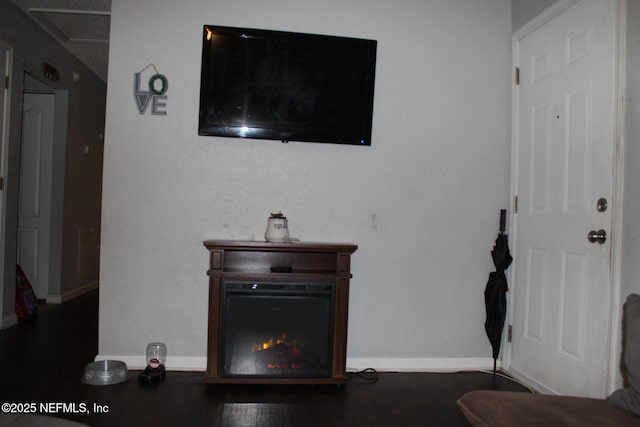 living area with a lit fireplace, visible vents, and baseboards