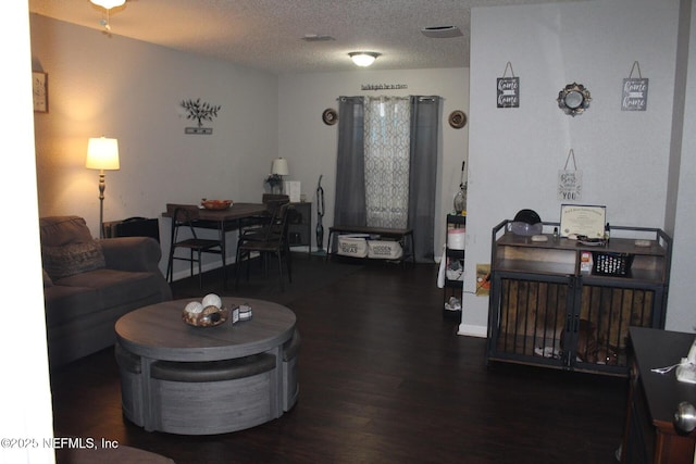 living area with a textured ceiling and dark wood finished floors