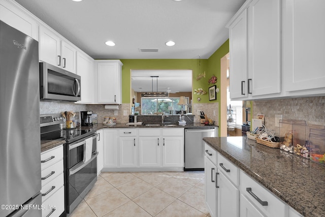 kitchen featuring light tile patterned flooring, stainless steel appliances, a sink, visible vents, and white cabinets