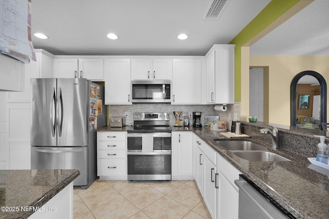 kitchen with appliances with stainless steel finishes, dark stone counters, white cabinetry, and a sink