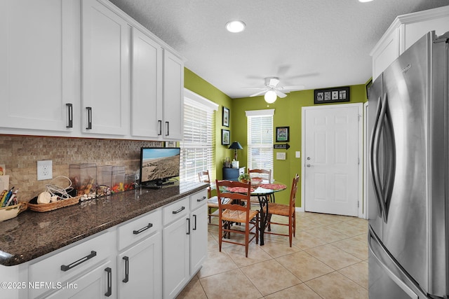 kitchen with light tile patterned floors, tasteful backsplash, freestanding refrigerator, and white cabinetry