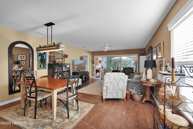 dining area featuring dark wood-style floors, arched walkways, ceiling fan, and baseboards