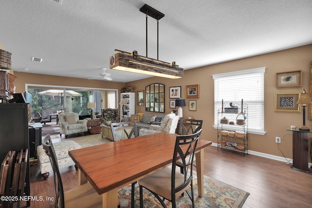 dining space featuring a healthy amount of sunlight, visible vents, wood-type flooring, and a textured ceiling