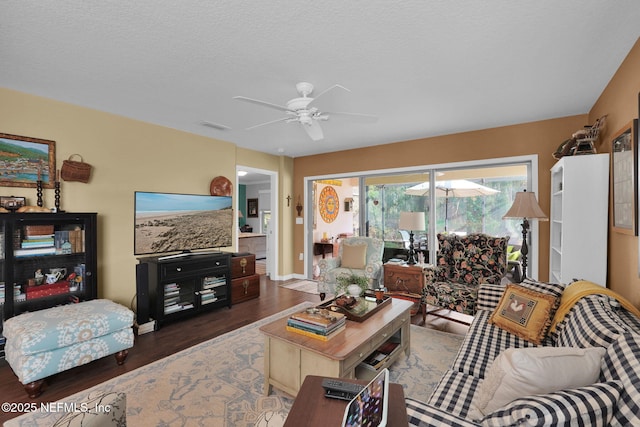 living room featuring a ceiling fan, visible vents, a textured ceiling, and wood finished floors