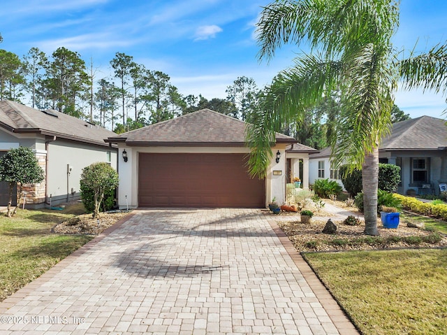 ranch-style house with an attached garage, an outdoor structure, decorative driveway, and stucco siding