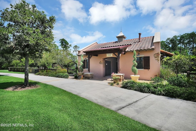 mediterranean / spanish home with a tiled roof, a front yard, and stucco siding