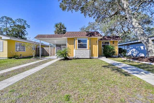 63 Catalina Cir, Saint Augustine, FL 32086 - view of front facade with an attached carport, fence, stone siding, roof with shingles, and a front yard