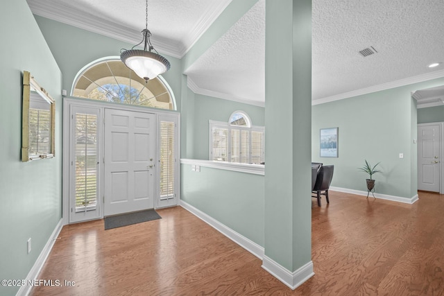 entrance foyer featuring a textured ceiling, visible vents, wood finished floors, and ornamental molding