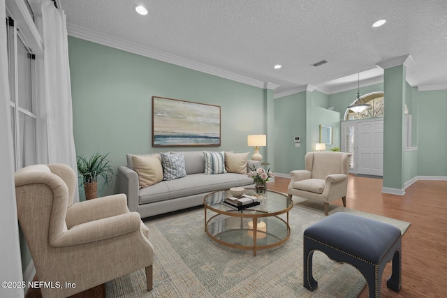 living room with baseboards, wood finished floors, crown molding, a textured ceiling, and recessed lighting