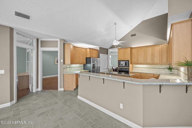 kitchen featuring a peninsula, stainless steel fridge, visible vents, and built in microwave