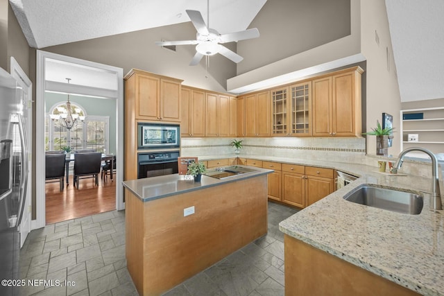 kitchen featuring stone tile floors, appliances with stainless steel finishes, light stone counters, a sink, and backsplash