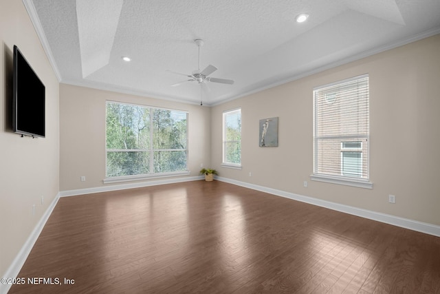 unfurnished room with crown molding, a raised ceiling, a textured ceiling, wood finished floors, and baseboards