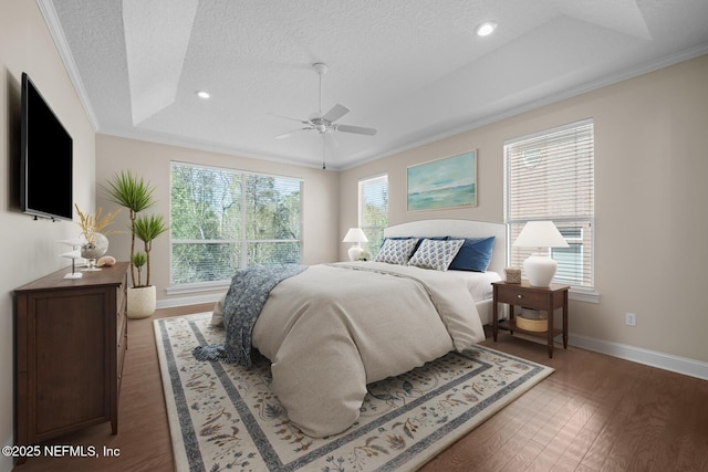 bedroom featuring wood finished floors, multiple windows, a raised ceiling, and crown molding