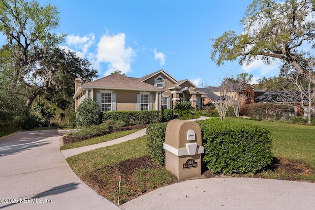 view of front of house with driveway, a front lawn, and stucco siding