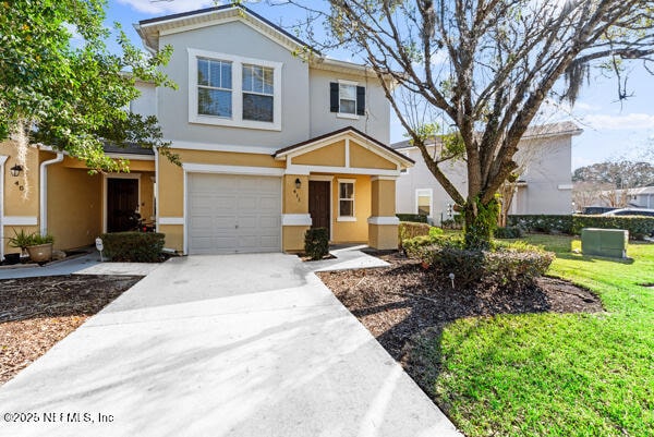 traditional home with a garage, driveway, a front lawn, and stucco siding