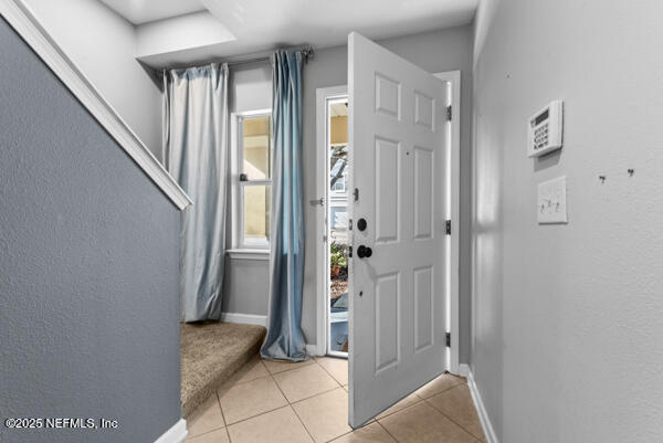 entryway with light tile patterned flooring and baseboards