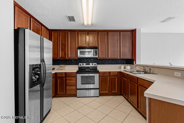 kitchen with light tile patterned floors, light countertops, visible vents, appliances with stainless steel finishes, and a sink