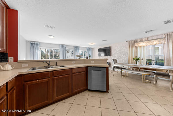 kitchen with dishwasher, light countertops, hanging light fixtures, and a sink