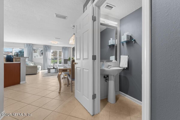 bathroom featuring a textured ceiling, baseboards, visible vents, and tile patterned floors