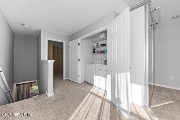 hallway with washing machine and dryer, baseboards, light colored carpet, and an upstairs landing