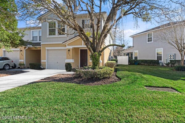 view of front of property with a garage, a front lawn, concrete driveway, and stucco siding