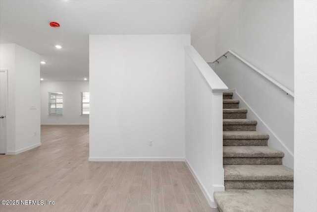 stairway with baseboards, wood finished floors, and recessed lighting