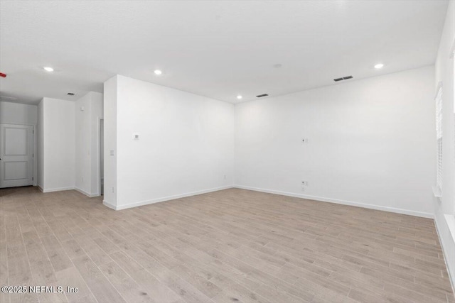 empty room with light wood finished floors, recessed lighting, visible vents, and baseboards