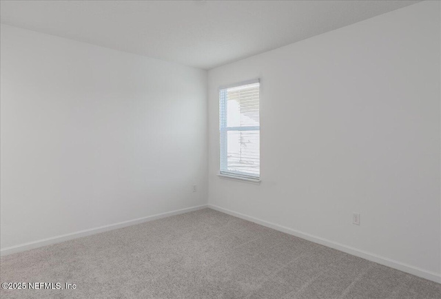 carpeted empty room featuring baseboards