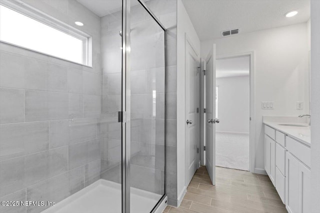 full bath featuring recessed lighting, vanity, visible vents, and a shower stall