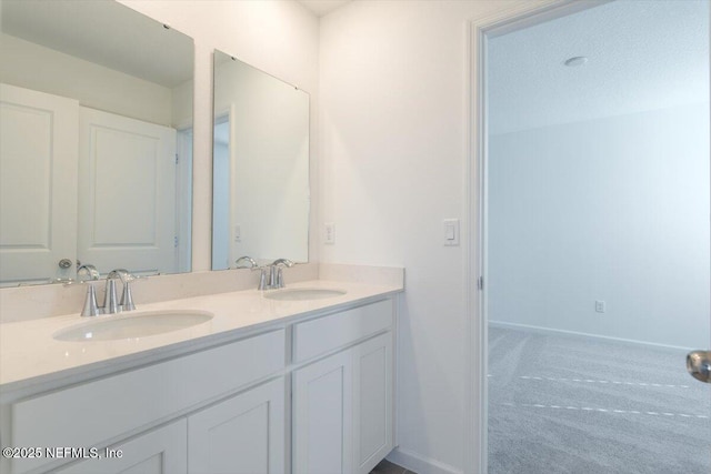 full bath with double vanity, a sink, and baseboards