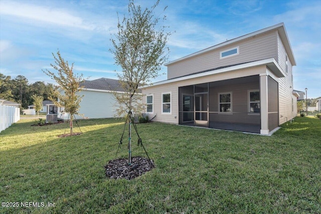 rear view of house with a lawn, fence, and a sunroom