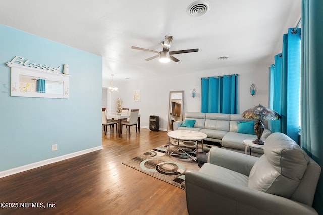 living area with baseboards, visible vents, dark wood-type flooring, and ceiling fan with notable chandelier