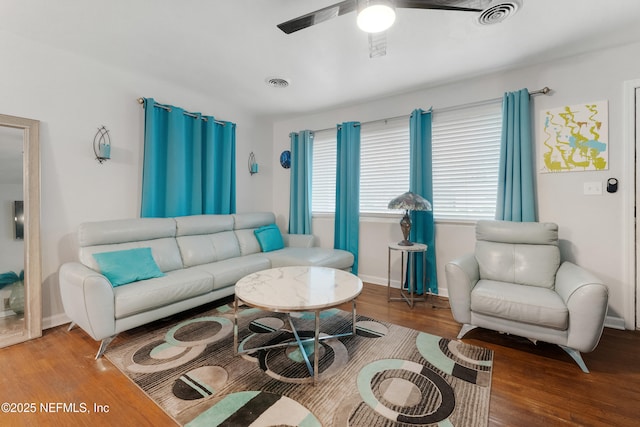 living area featuring visible vents, ceiling fan, baseboards, and wood finished floors