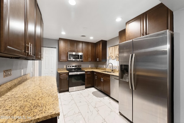 kitchen with dark brown cabinetry, light stone counters, marble finish floor, stainless steel appliances, and recessed lighting