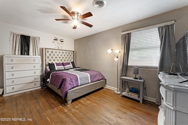 bedroom with ceiling fan, wood finished floors, visible vents, and baseboards