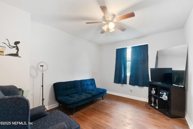 living area featuring wood finished floors, a ceiling fan, and baseboards