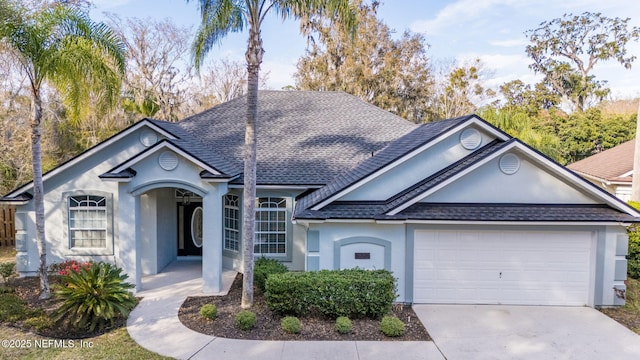 ranch-style home featuring a garage, driveway, a shingled roof, and stucco siding