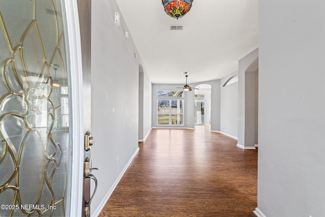 entrance foyer featuring arched walkways, wood finished floors, visible vents, and baseboards