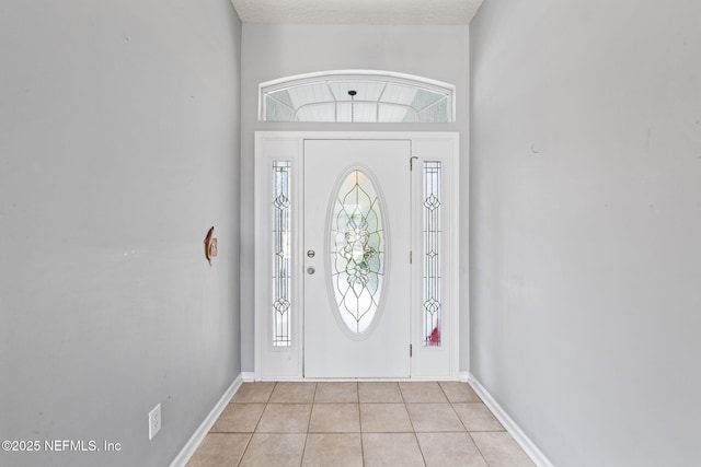 foyer entrance featuring light tile patterned flooring and baseboards