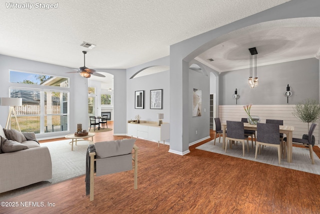 living area with ceiling fan, a textured ceiling, and wood finished floors