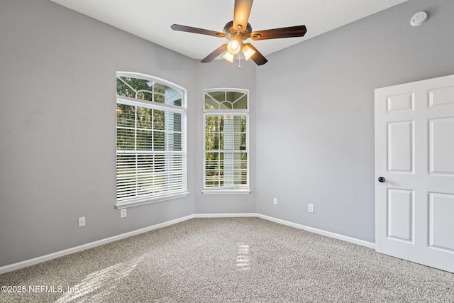 carpeted empty room with ceiling fan and baseboards