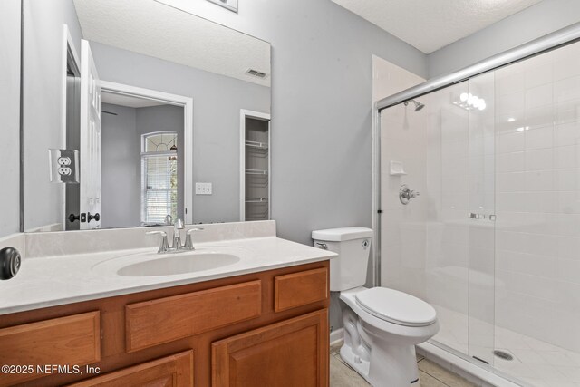 bathroom featuring a stall shower, vanity, toilet, and a textured ceiling