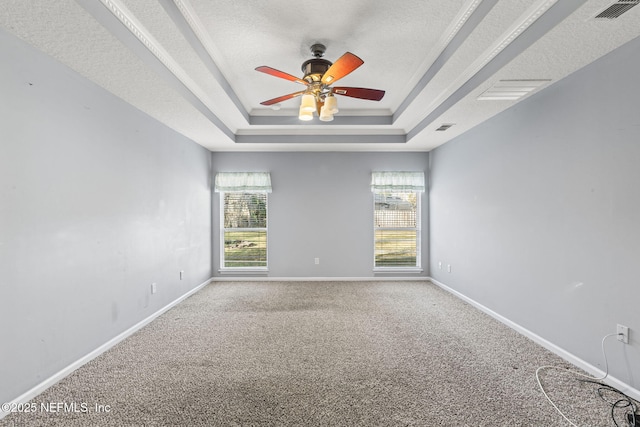 carpeted empty room featuring a textured ceiling, a tray ceiling, visible vents, and baseboards