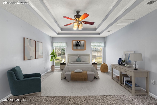 bedroom with a tray ceiling, visible vents, carpet, and multiple windows