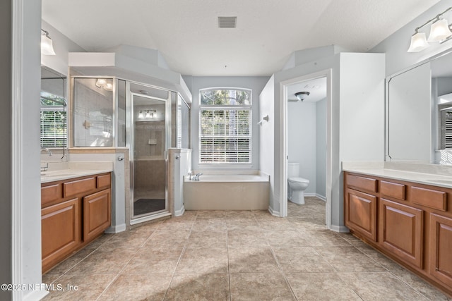 bathroom featuring a stall shower, two vanities, visible vents, and toilet