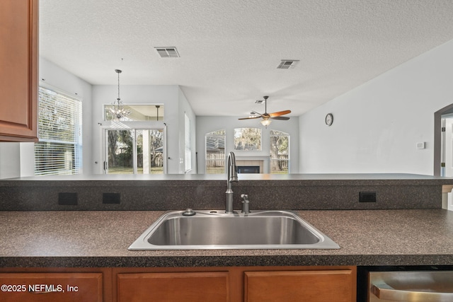 kitchen with dark countertops, a fireplace, a sink, and stainless steel dishwasher