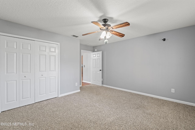 unfurnished bedroom with carpet floors, a closet, visible vents, a textured ceiling, and baseboards