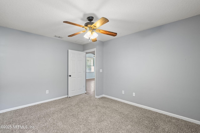 unfurnished room featuring visible vents, a ceiling fan, carpet flooring, a textured ceiling, and baseboards